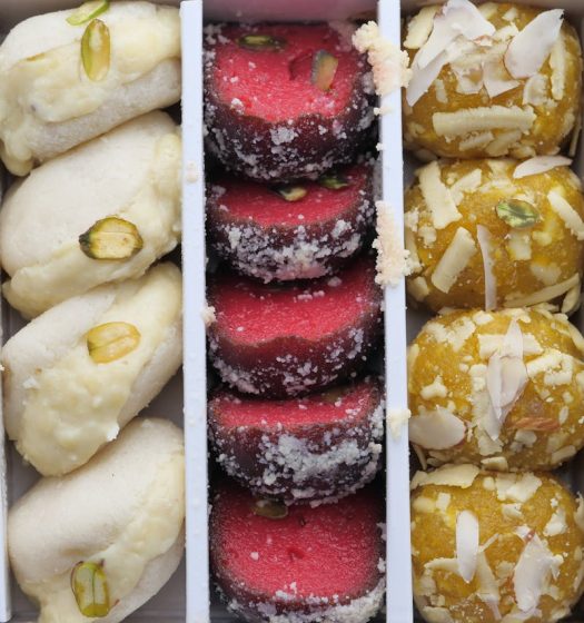 A vibrant collection of Indian sweets featuring almonds, pistachios, and coconut.